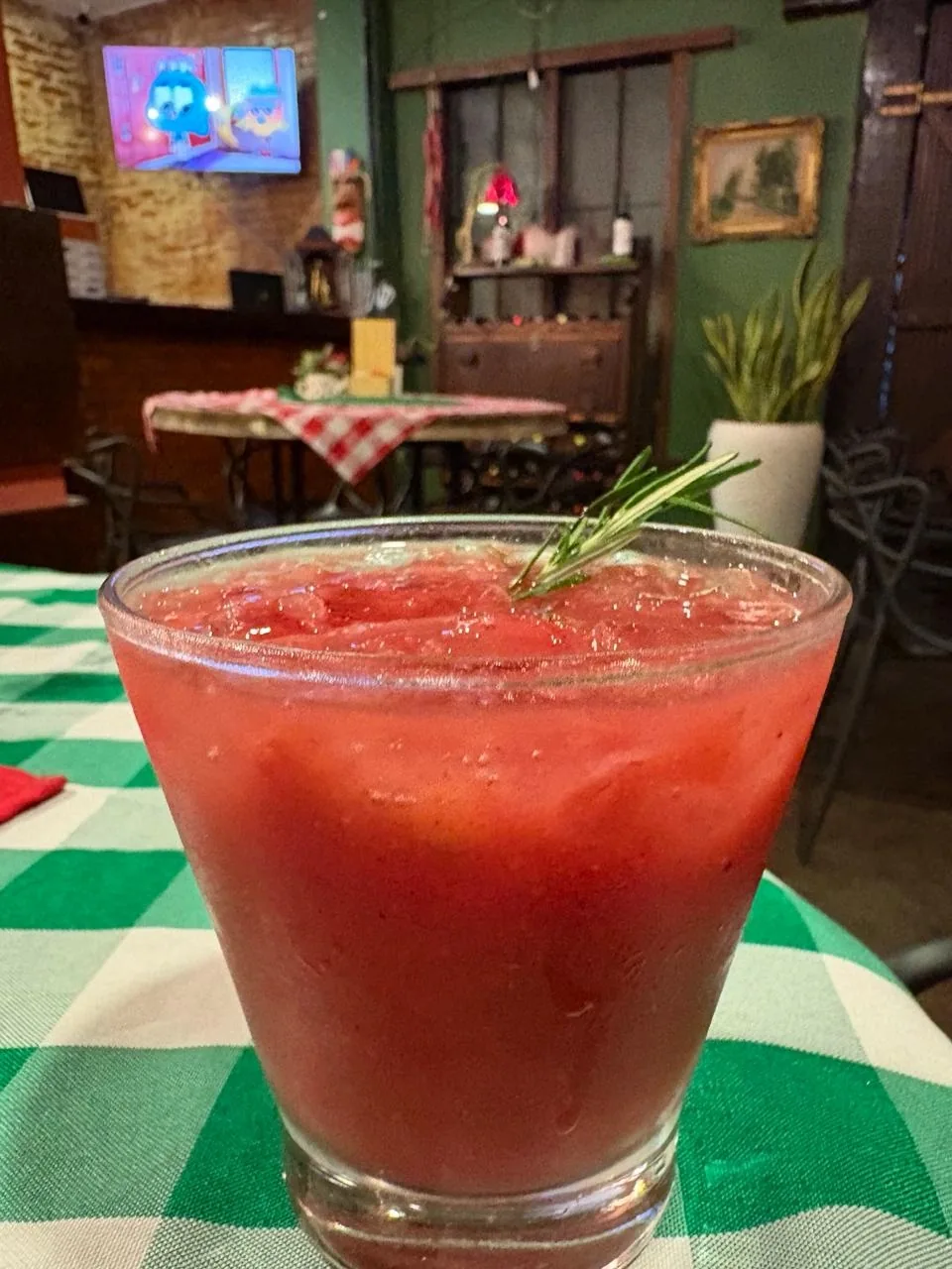 Drink vermelho com alecrim servido na taça