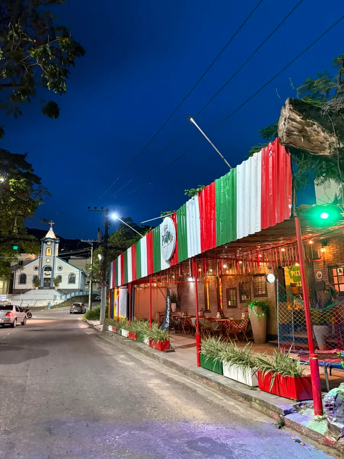 Fachada noturna da Casa Piatto iluminada com as cores da bandeira da Itália