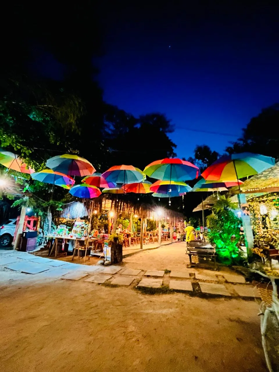 Caminho do Dedo de Moça coberto por guarda-chuvas coloridos iluminados à noite
