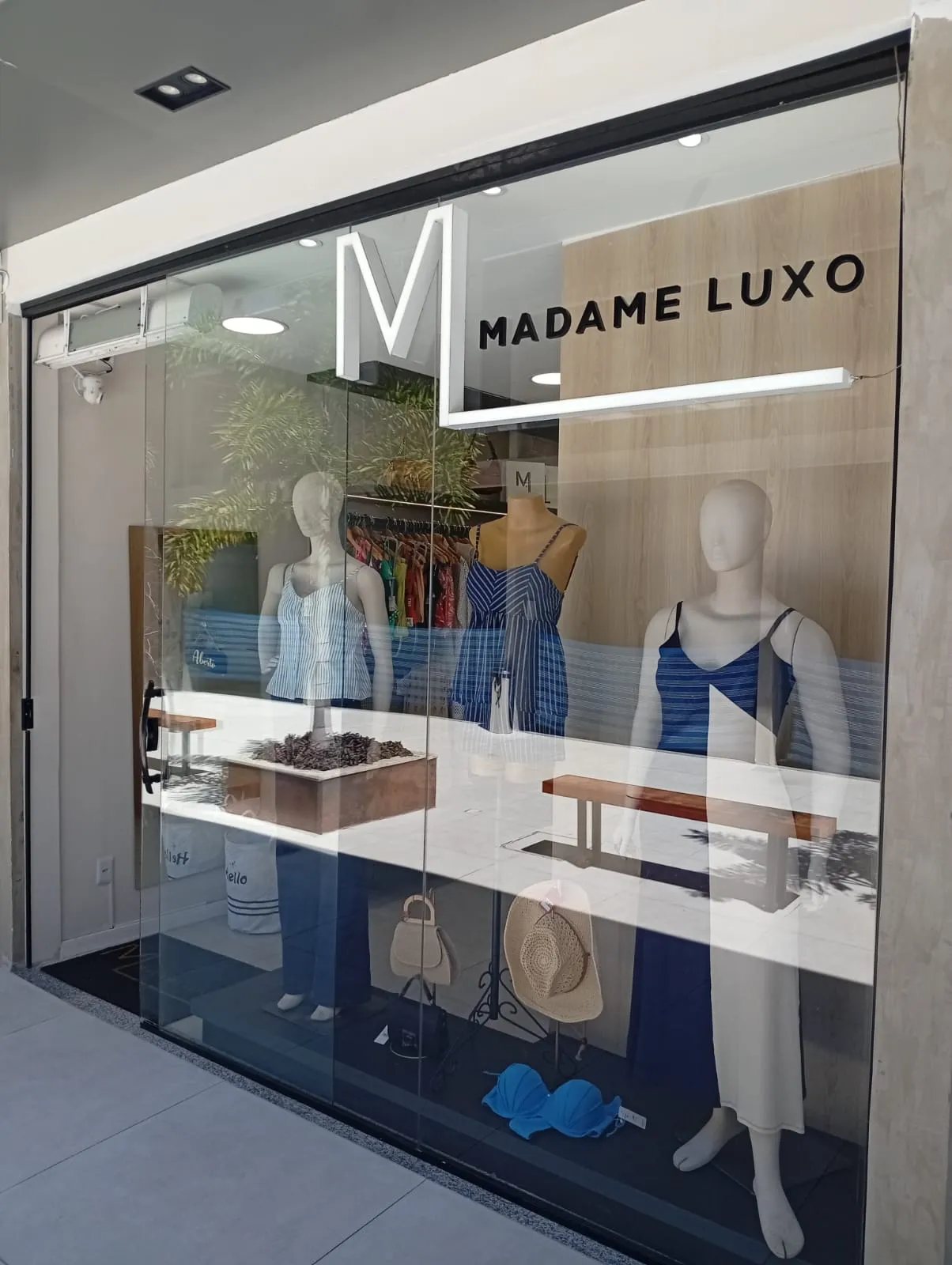 Fachada da loja Madame Luxo com vitrine exibindo vestidos da nova coleção e logo moderno